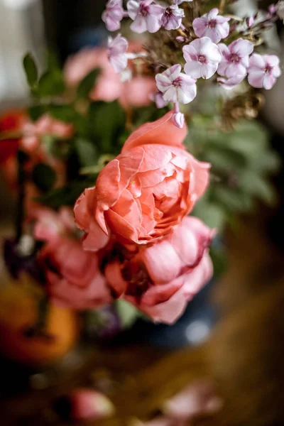 一束明亮的玫瑰花 放在桌子上的蓝色花瓶里的天麻花 一朵橙子 自然光 漂亮的背景 — 图库照片