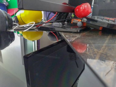 Pomodoro mutfak zamanlayıcısı ahşap bir masanın üzerinde duran kırmızı domates şeklinde ve etrafında renkli nesneler var.