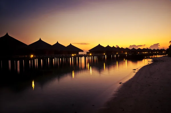 Tropical huts along a beach at sunset — Stock Photo, Image