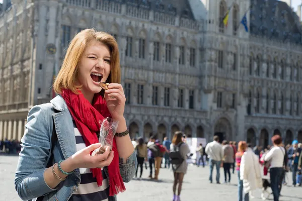 Žena jíst čokoládu na grand place v Bruselu — Stock fotografie