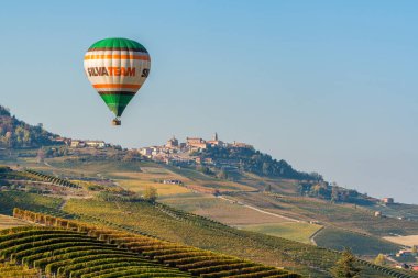 La Morra köyünü çevreleyen sonbahar mevsimi boyunca tepeler ve üzüm bağları üzerinde uçan sıcak hava balonu. Langhe bölgesinde, Cuneo, Piedmont, İtalya.