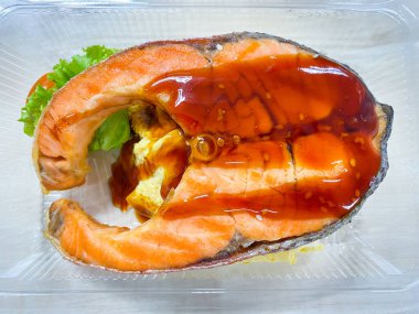 Masadaki yemek kabında salata ile ızgara somon balığı.