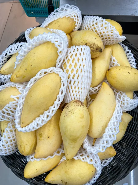 Sarı mango sepette satılık bir baloncuğa sarılı.
