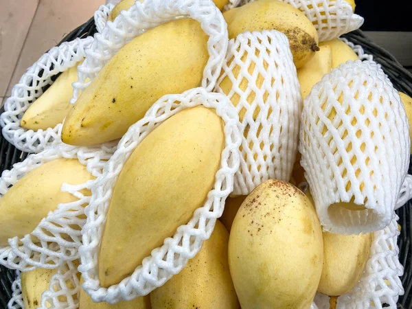 Sarı mango sepette satılık bir baloncuğa sarılı.