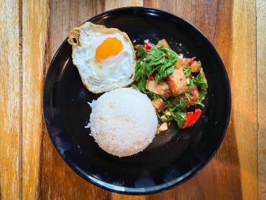 Kızarmış domuz ve fesleğenli pilav ve masada kızarmış yumurta.