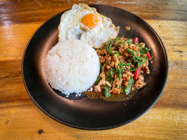 Kızarmış domuz ve fesleğenli pilav ve masada kızarmış yumurta.