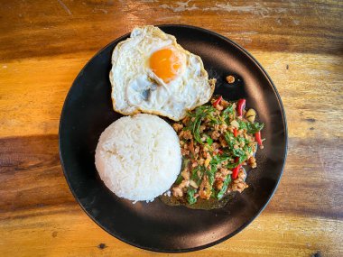 Kızarmış domuz ve fesleğenli pilav ve masada kızarmış yumurta.