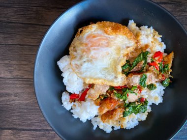 Kızarmış domuz ve fesleğenli pilav ve masada kızarmış yumurta.