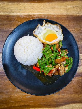 Kızarmış domuz ve fesleğenli pilav ve masada kızarmış yumurta.