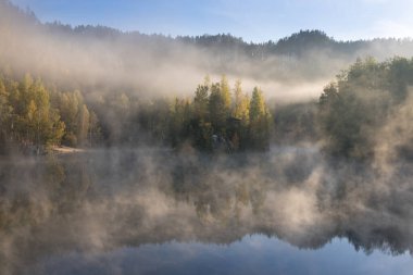 Sonbaharda gölü olan güzel renkli ağaçlar, manzara fotoğrafları. Sonbahar sonu ve kış başında. Açık hava ve doğa. İnanılmaz sisli bir sabah. Göl kıyısında. Sonbahar gölü üzerinde sis.