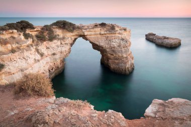 Okyanusun üzerindeki doğal kemer. Marinha sahilindeki doğal mağaralar, Algarve, Lagoa Portekiz. Sahilde taş kemer. Yaz mevsimi.