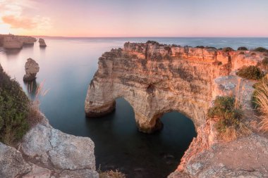 Okyanusun üzerindeki doğal kemer. Marinha sahilindeki doğal mağaralar, Algarve, Lagoa Portekiz. Sahilde taş kemer. Yaz mevsimi.