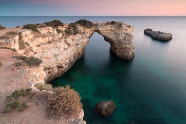 Okyanusun üzerindeki doğal kemer. Marinha sahilindeki doğal mağaralar, Algarve, Lagoa Portekiz. Sahilde taş kemer. Yaz mevsimi.