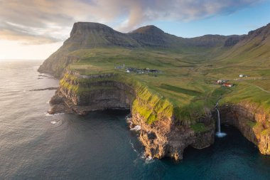 Gorgeous morning scene of Mulafossur Waterfall. Amazing summer view of Vagar island, Faroe Islands, Denmark, Europe. Beauty of nature concept background.