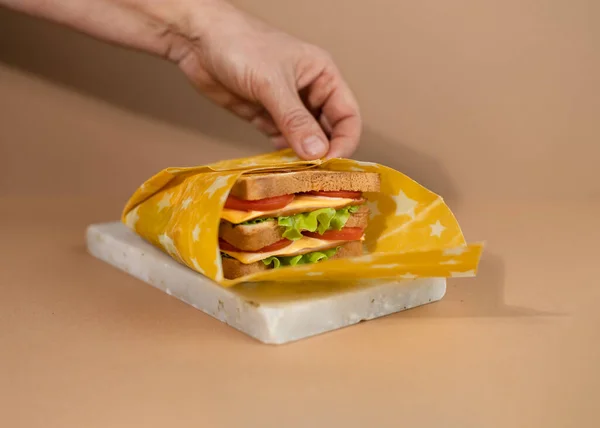 トーストしたパンスライス チーズ 新鮮なサラダを有機再利用可能な蜜蝋紙で包んだ伝統的なサンドイッチ サンドイッチの日を祝う — ストック写真