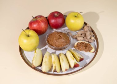 Cam bardakta fıstık ezmesi ve sicim torbasında olgun elmalar. Fıstık ezmesini elma dilimine dök. Lezzetli atıştırmalıklar vücudu besinlerle doldurur..