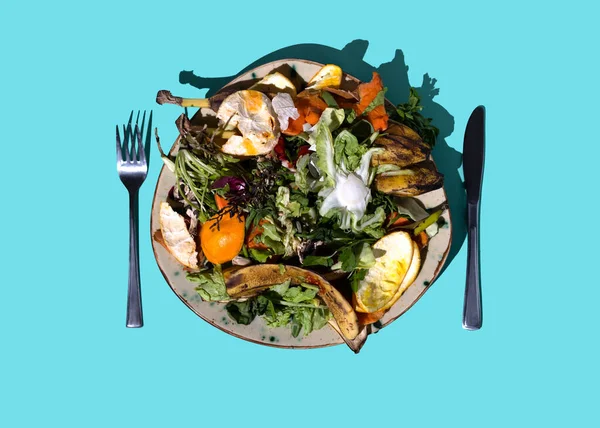 Reducing food waste concept. Kitchen leftovers from a meal and blemished fruits and vegetables on plate for for recycling and composting. Zero waste and caring for environment. Garbage sorting