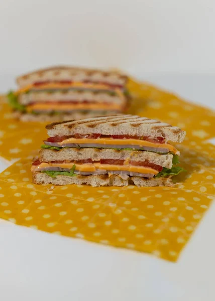 En traditionell smörgås gjord på rostade brödskivor, ost, skinka, färsk sallad insvept i ekologiskt bivaxpapper. — Stockfoto