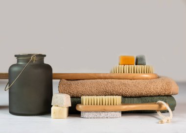 Ev yapımı bitkisel sabun ve yeşil ve bej havlu üzerinde doğal kılları olan bambu masaj fırçası. Çevre dostu, ayrıştırılabilir, sıfır atık.