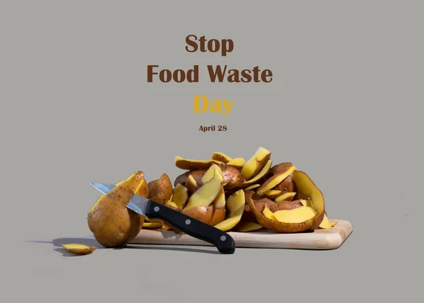 Concept of Stop food waste day. Potato peels are one of the most commonly discarded items during food prep. Gray background.