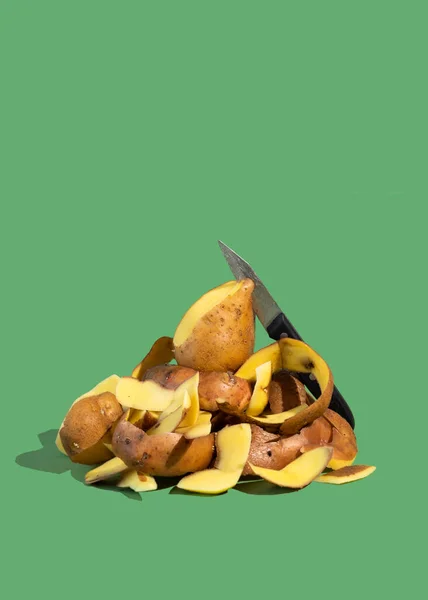 Concept of Stop food waste day. Potato peels are one of the most commonly discarded items during food prep. Green background.