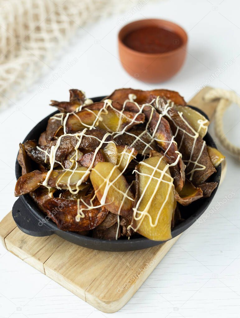 Potato nachos in a cast iron skillet. Crispy baked potato skins are rich in nutrients. Vegetable peels are one of the most commonly wasted foods in cooking. Processing of food waste.