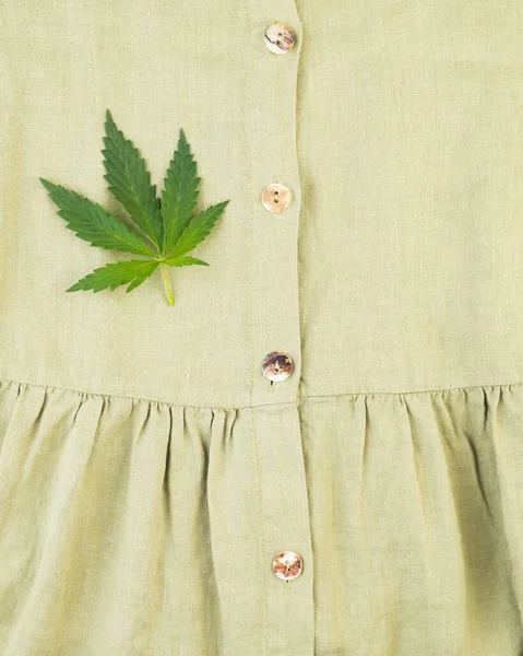 Close-up of an organic hemp fiber dress with a hemp leaf. Hemp textile fibers are usefulness, versatility and durability.