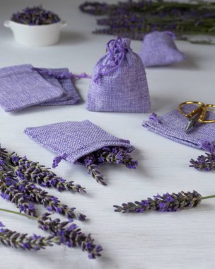 Lavender flowers and purple sacs on a white background. Homemade lavender sachets for aroma therapy and moth protection. Vertical shot.