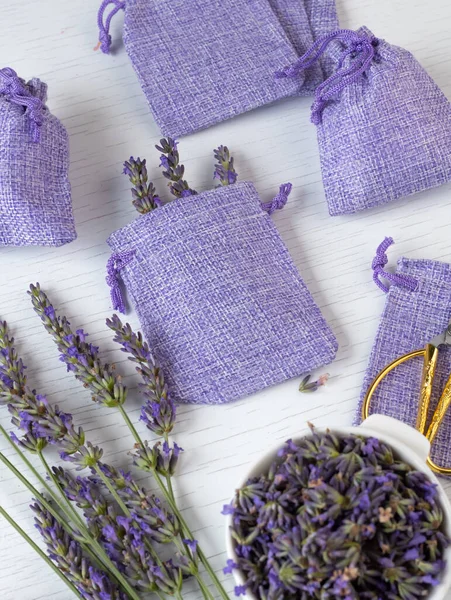 Lavender flowers and purple sacs on a white background. Homemade lavender sachets for aroma therapy and moth protection. Vertical shot.
