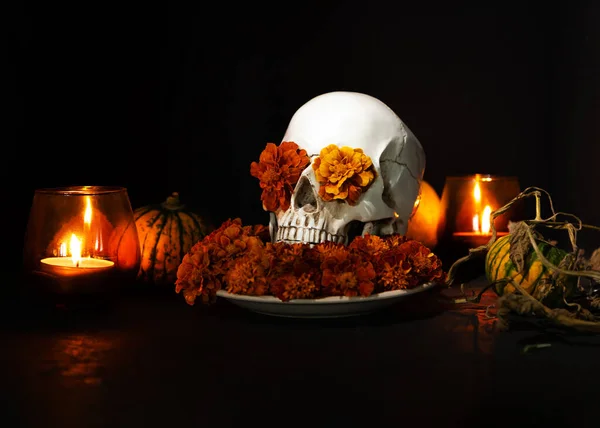 Skull, Burning candles and orange marigold flowers on black background. Concept of Dia de los muertos day or day of the dead. Dark halloween banner.