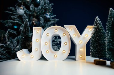 Joy harfleri mavi arka plan ve Noel ağacına karşı. Tatil arkaplanı. 