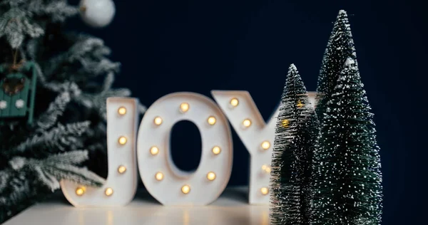 Die Buchstaben Joy Vor Blauem Hintergrund Und Weihnachtsbaum Hintergrund Der lizenzfreie Stockfotos