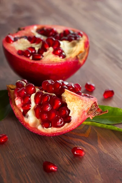 Färsk mogen granatäpple med blad på en planka. — Stockfoto