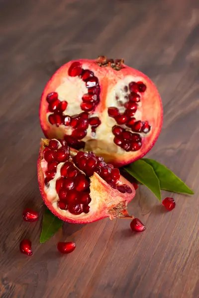 Färsk mogen granatäpple med blad på en planka. — Stockfoto