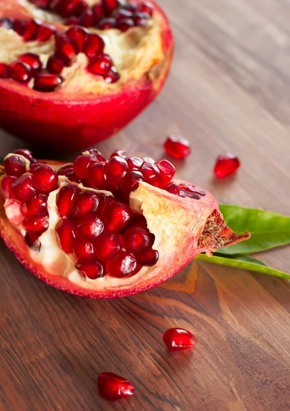 Mogen granatäpple med blad på en planka. — Stockfoto