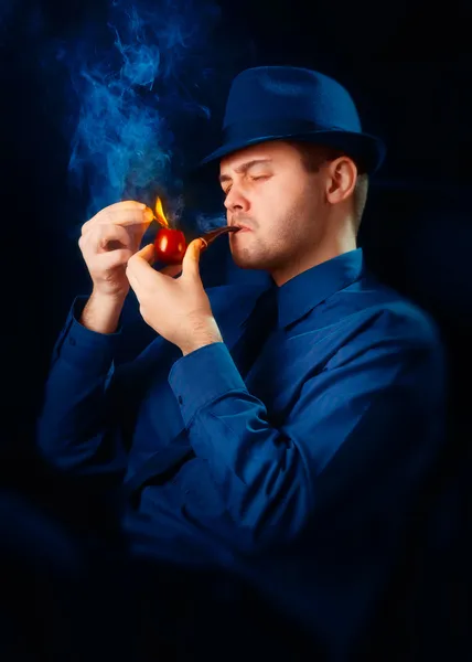 Mann med hatt som tenner sin pipe med fyrstikk – stockfoto