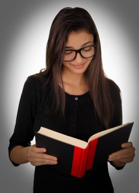 Gözlüklü kız kitap okuyor.