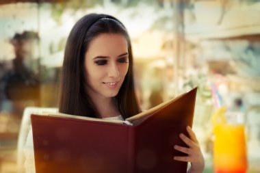 genç kadın bir restoran menüsünden seçerek