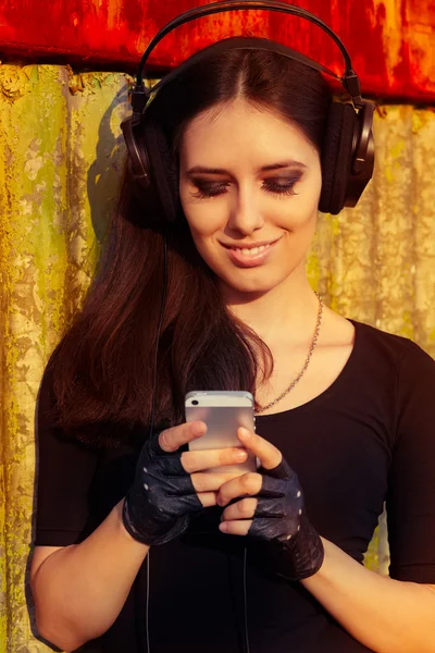 Fille avec de gros écouteurs et téléphone intelligent sur fond grunge — Photo