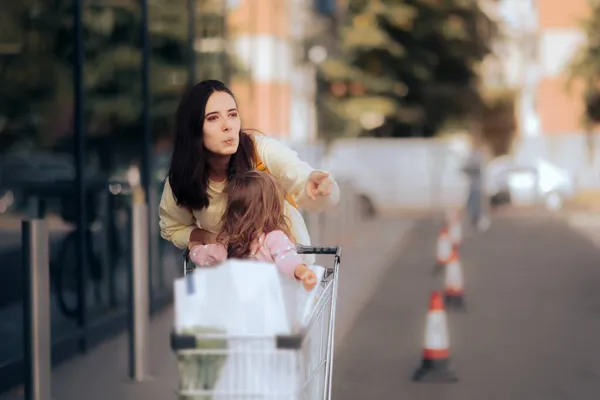 Mutter Zeigt Auf Etwas Außerhalb Eines Einkaufszentrums Und Schiebt Einkaufswagen — Stockfoto