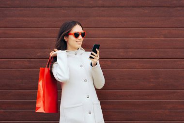 Alış veriş yapan kişi kalp şeklinde gözlük takan akıllı bir telefon tutuyor.