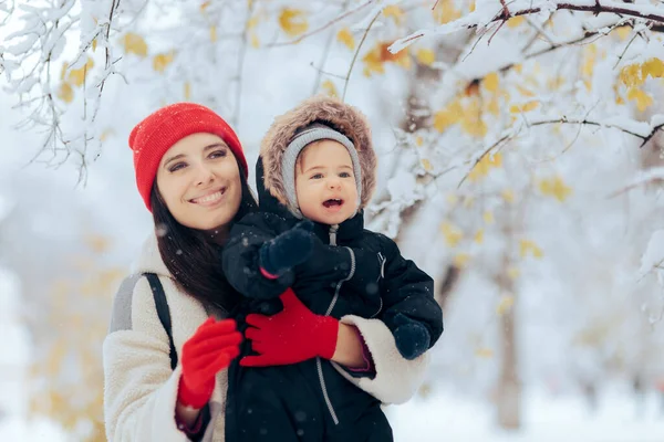 快乐的妈妈抱着快乐的宝宝欣赏着雪 — 图库照片