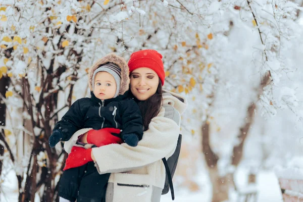 快乐的妈妈抱着快乐的宝宝欣赏着雪 — 图库照片