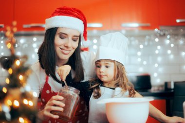 Küçük kız annesiyle kavanozdan şeker alıyor.