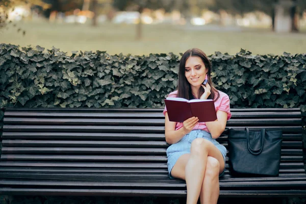 女人坐在公园的长椅上看书 — 图库照片