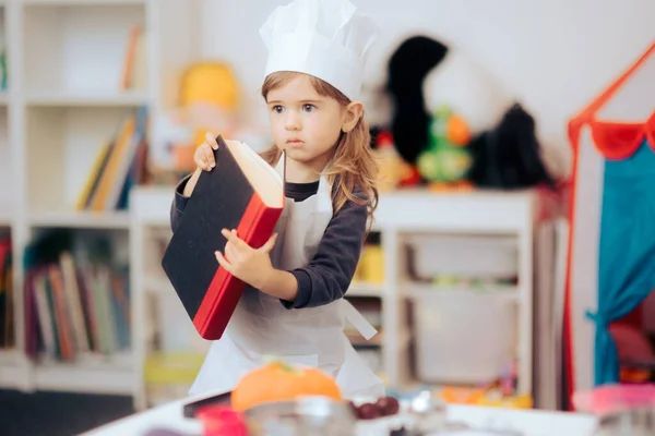 Petite Fille Portant Chapeau Chef Tablier Tenant Livre Cuisine — Photo