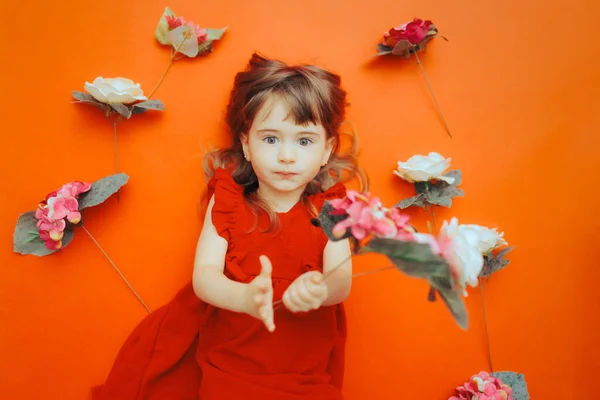 Κοριτσάκι Περιτριγυρισμένο Από Λουλούδια Κόκκινο Φόντο — Φωτογραφία Αρχείου