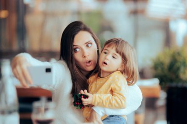 Anne ve kızı bir restoranda selfie çekiyor.