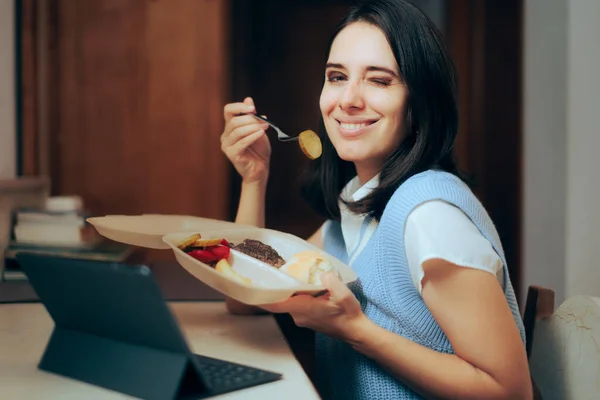 幸せな女性家庭で働くテイクアウト食品を食べる — ストック写真