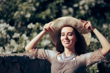 Hasır Şapkalı Kadın Yaz boyunca Güneş Işığının tadını çıkarıyor 